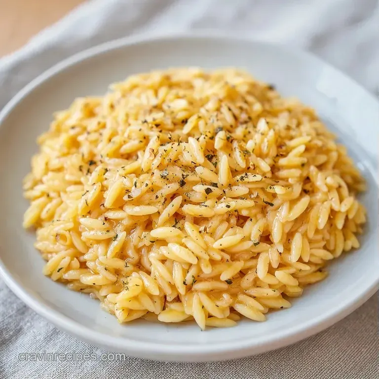 Elegant white bowl of creamy pasta garnished with bright green herbs and a swirl of melted butter on a marble top.